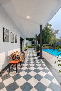 a house with a checkered floor and a swimming pool at SaffronStays Mayfair Gardens - 4BR pet-friendly pool villa with patio, den, board games & modern interiors near jetty in Alibaug