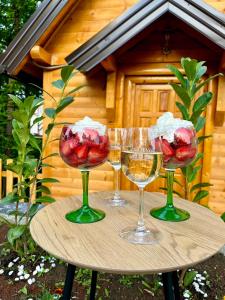 three wine glasses on a table in front of a cabin at Vila Šibovi in Banja Luka