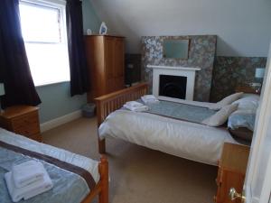 1 dormitorio con 2 camas individuales y chimenea en Victoria Lodge, en Sandown