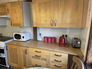 a kitchen with wooden cabinets and a counter with a microwave at Captivating Tudor 2 Bedroom Apartment in Ipswich in Ipswich