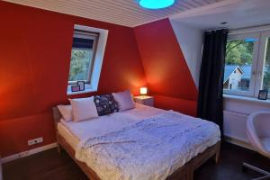 a bedroom with red walls and a bed with white sheets at Stadtnahe Familienvilla in Oersdorf