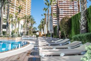 een rij chaise ligstoelen naast een zwembad in een resort bij AR Diamante Beach & SPA Hotel 4 SUP in Calpe