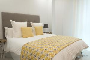 um quarto com uma cama grande com almofadas amarelas e brancas em Living4malaga Blue Bay em Málaga