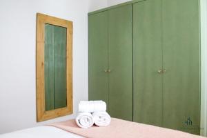 sypialnia z zielonymi szafkami i 2 rolkami ręczników w obiekcie Living4malaga Spring Boutique w Maladze