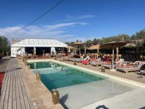 a swimming pool with lounge chairs and umbrellas at Agafay, La Ferme Nomade Bivouac in El Karia