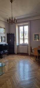 een woonkamer met een houten vloer en een groot raam bij Uncle's house, 150 mq only two stops from Duomo in Milaan