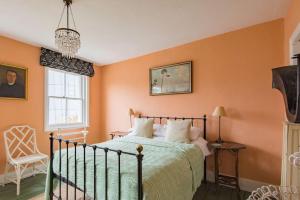 a bedroom with orange walls and a bed and a chair at Folkestone Terrace - quirky vibe holiday home in Kent