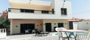 a house with a balcony with a table and chairs at Musharbash in Al Baḩḩāth