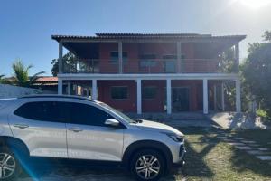 un coche blanco estacionado frente a una casa en Casa de Praia em condomínio, en Vera Cruz de Itaparica