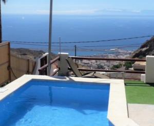 a person sitting in a chair next to a swimming pool at Nueva Casa rural piscina privada in Santa Cruz de Tenerife