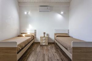 イスピカにあるVilla Pinella by Villa Plusの白い壁とウッドフロアの客室で、ベッド2台が備わります。