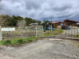 a fence in front of a yard with a house at Cabañas El Ermitaño in Puerto Montt