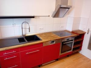 a kitchen with red cabinets and a sink at Geräumige FeWo nahe Nürnberg in Oberasbach