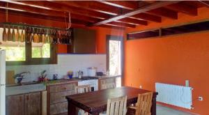 cocina con paredes de color naranja y mesa de madera en Casa independiente, a tres km de Moratalla, en Moratalla
