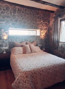 una camera da letto con un letto e un muro di pietra di Casa La Poza a Moratalla