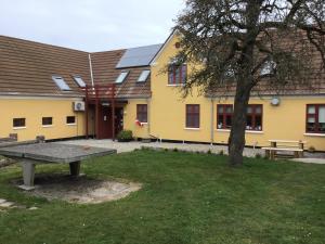 a yellow building with a picnic table and a tree at Pension Stenvang in Onsbjerg