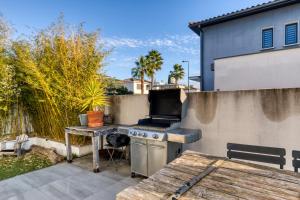 a patio with a grill and a wooden table at Maison Melgorienne in Mauguio