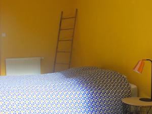 a bedroom with a bed and a ladder on a yellow wall at Gîte Remiremont, 4 pièces, 6 personnes - FR-1-589-411 in Remiremont