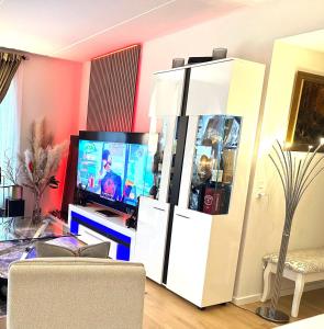 a living room with a tv and a white entertainment center at Attraktiv lejlighed in Odense