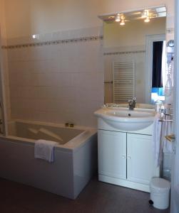 a bathroom with a tub and a sink and a bath tub at Logis Hôtel Le Cygne in Le Bugue