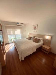 um quarto com uma grande cama branca e pisos em madeira em Apart Hotel Rio Grande em Rosário