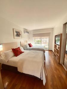 two beds in a room with wooden floors at Apart Hotel Rio Grande in Rosario