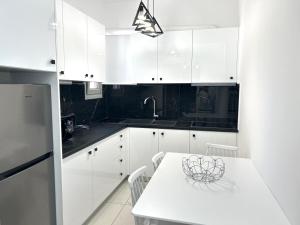 cocina con armarios blancos y mesa blanca en Athens white apartments, en Atenas