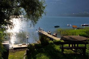a dock on a lake with people swimming in the water at Appartementhaus Karantanien am Ossiacher See in Ossiach
