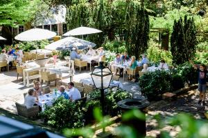 a group of people sitting at tables in a garden at Villa Beukenhof in Oegstgeest