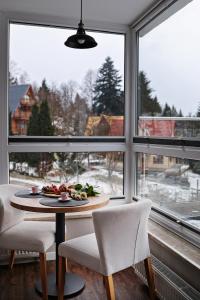 a table with a plate of food in a room with windows at Keller Apart K12 - Taras z widokiem na wyłączność i klimatyzacją GRATIS in Porąbka