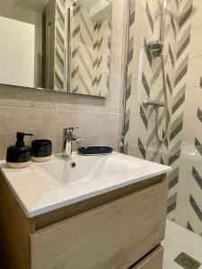 La salle de bains est pourvue d'un lavabo blanc et d'un miroir. dans l'établissement Appartement calme et bien décoré, cours Fauriel, à Saint-Étienne