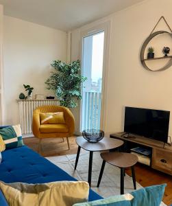 un salon avec un canapé bleu et une télévision dans l'établissement Appartement calme et bien décoré, cours Fauriel, à Saint-Étienne