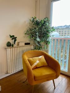 une chaise jaune dans un salon avec une fenêtre dans l'établissement Appartement calme et bien décoré, cours Fauriel, à Saint-Étienne