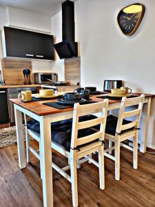 a kitchen with a table with chairs and a clock on the wall at Lions Place Premium Apartments COMFORT optionaler Zugang zum SPA- Bereich in Heidenheim an der Brenz