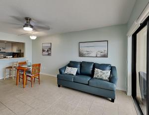 uma sala de estar com um sofá azul e uma mesa em Ocean Sands 505 em St. Pete Beach