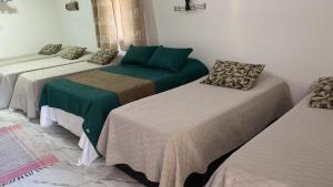 drie bedden in een kamer met groene en bruine lakens bij Hotel Fazenda Chiminelli in Cachoeiras de Macacu