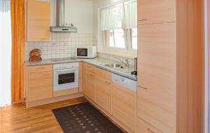 クライナルにあるAmazing Apartment In Kleinarl With 3 Bedroomsのキッチン(木製キャビネット、シンク、電子レンジ付)