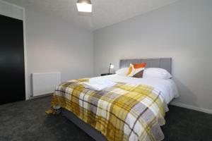 Un dormitorio con una cama con una manta amarilla y blanca. en Signature - Glen Garry House, en East Kilbride