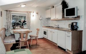 ヴァークラインにあるAmazing Apartment In Wagrain With Wifiの白いキャビネット、シンク、テーブル付きのキッチンが備わります。