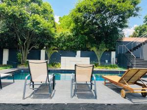 two chairs and a table and a bench next to a pool at Tranquil Escapes Bramley in Johannesburg