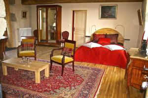 a bedroom with a bed and two chairs and a rug at Chambre d'hôtes de Pirieuc in Meillac