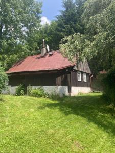 eine alte Scheune mit rotem Dach auf einem Grasfeld in der Unterkunft Chaloupka in Žacléř