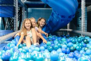 três meninas sentadas numa piscina insuflável de bolas azuis em Rezydencja AQUA em Szklarska Poręba