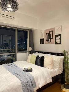 um quarto com uma cama com lençóis brancos e uma janela em The Serene Escape Rockwell Makati City View 1BR em Manilla