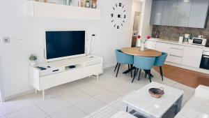 ein Wohnzimmer mit einem TV und einem Tisch mit Stühlen in der Unterkunft Villa with pool La Zenia in Orihuela