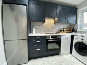 una cocina con armarios negros y un aparato blanco en Cottage 437 - Ballyconneely, en Ballyconneely