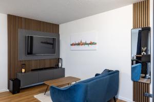 ein Wohnzimmer mit 2 blauen Stühlen und einem TV in der Unterkunft Sunnybelle Appartements Dresden I in Dresden