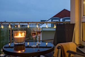 una mesa con copas de vino y una vela en el balcón en Sunnybelle Appartements Dresden I en Dresden