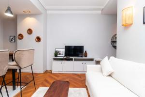 een woonkamer met een witte bank en een tv bij Apartment Center of Paris by Studio prestige in Parijs