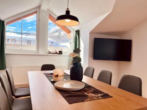 een eetkamer met een tafel en een tv bij Landhaus Alpenzeit in Arzl im Pitztal